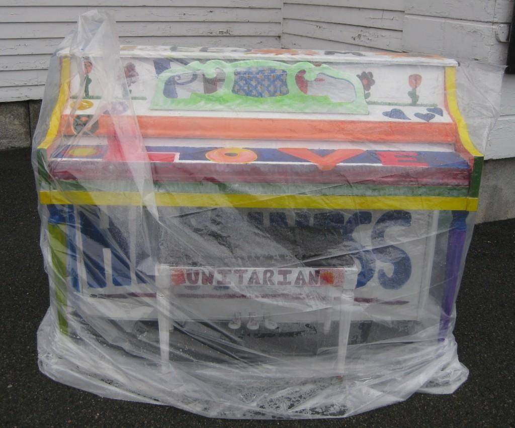 Plastic covers and protects the peace, love, and hope piano from rain in front of the Unitarian church. | by Stephanie Petrovick